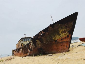 Abandoned boat on beach against clear sky