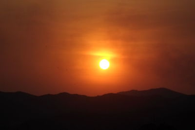 Scenic view of silhouette mountains against orange sky