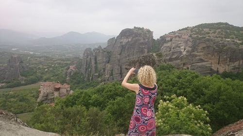 Rear view of woman on rock against sky