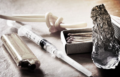 High angle view of syringe with lighter and matchsticks on table