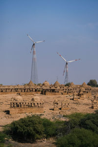 View of wind turbines behind ruins of bada bagh against sky