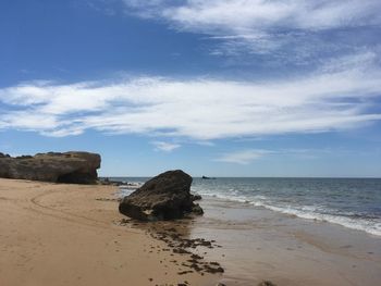 Rock formation on beach against sky