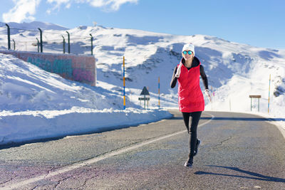 Full length of woman walking on snow covered mountain