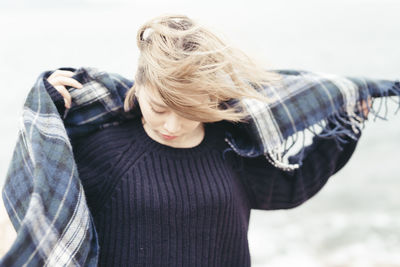 Woman wearing scarf at beach during winter