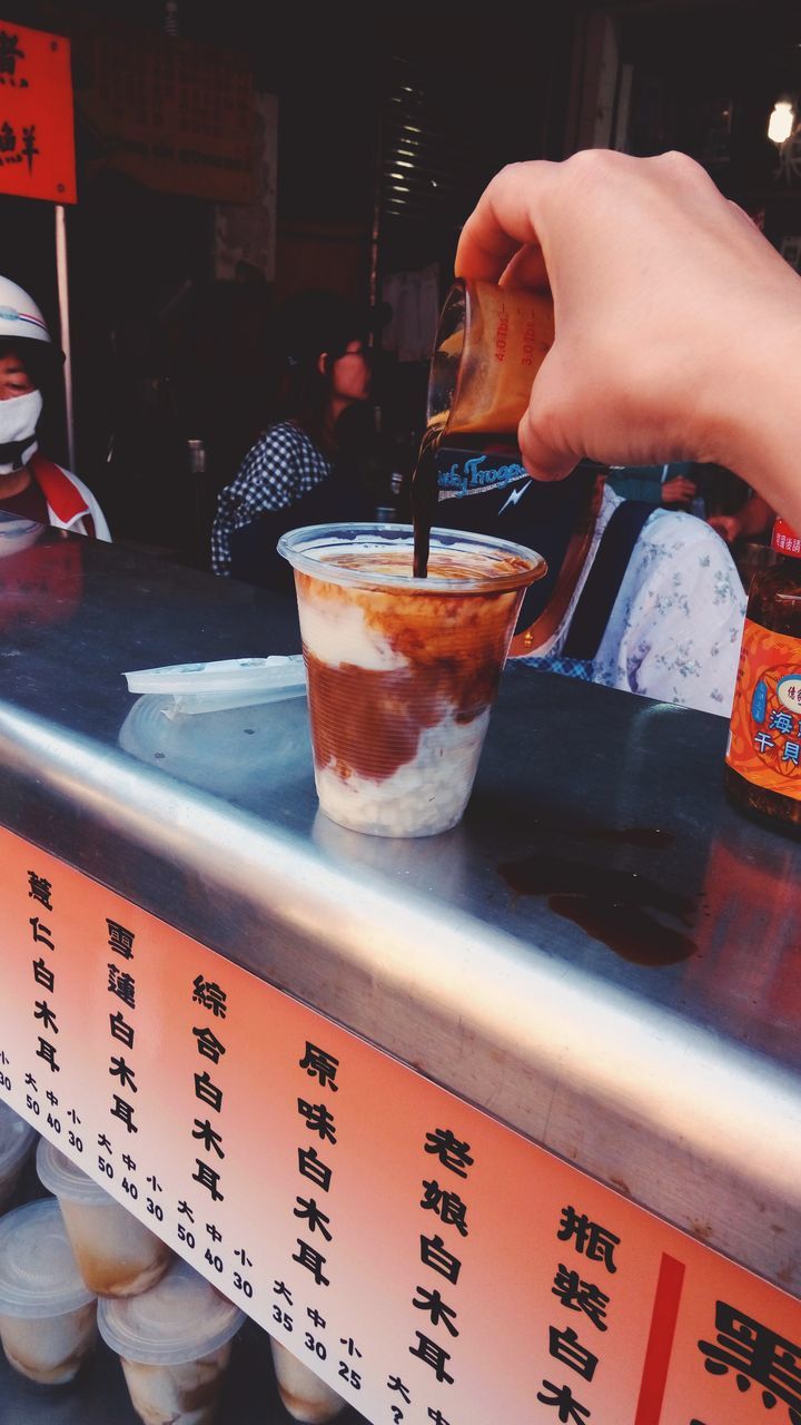 CLOSE-UP OF HAND HOLDING DRINK WITH TABLE