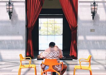 Rear view of man sitting on chair at table