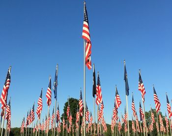 Low angle view of red flags against clear blue sky