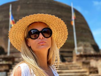 Portrait of woman wearing sunglasses while standing at historic place
