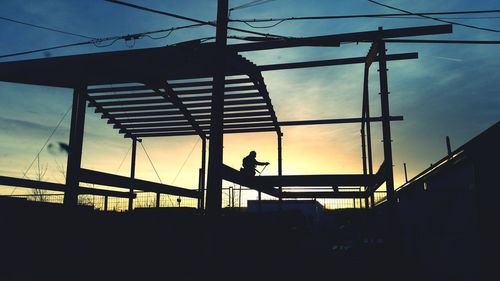 Low angle view of silhouette worker at construction site against sky