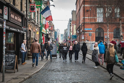 People walking on street amidst buildings in city