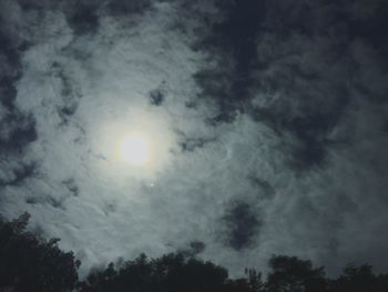 Low angle view of trees against cloudy sky