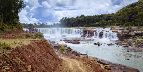 Scenic view of waterfall in forest against sky