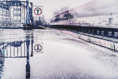 Road sign by canal against sky in city