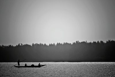 Silhouette people on boat against sky