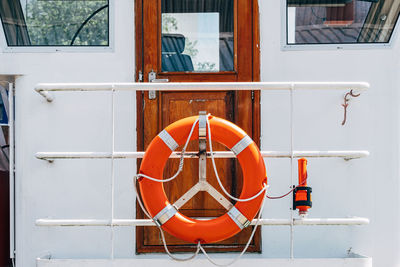 Lifebuoy hanging on handrail in front of wooden door
