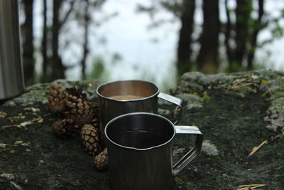 Close-up of coffee cup on table against trees in forest