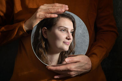 Conceptual mother holding a mirror and reflexion of daughter