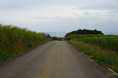 Road amidst grass against sky