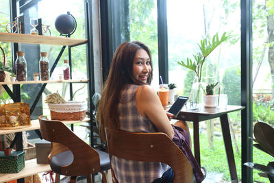 Portrait of young woman sitting on table by window