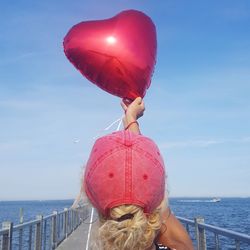 Rear view of woman with pink umbrella against sea