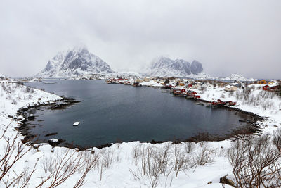 Scenic view of frozen lake by snowcapped mountain against sky