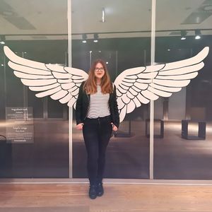 Full length portrait of young woman standing against wall
