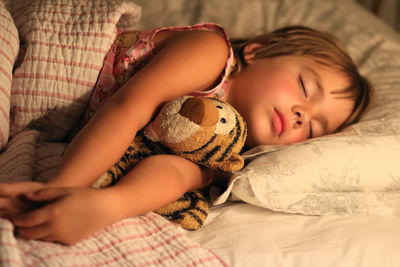 Close-up of cute boy sleeping with stuffed toy on bed at home