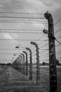 Barbed wire fence on field against sky