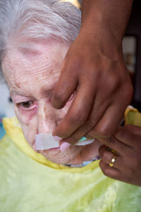 Elderly woman receiving facial hair removal from african american caregiver