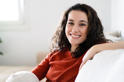 Portrait of young woman sitting on bed at home