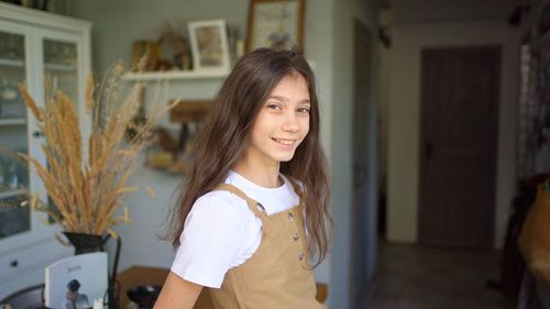 Portrait of smiling young woman standing at home