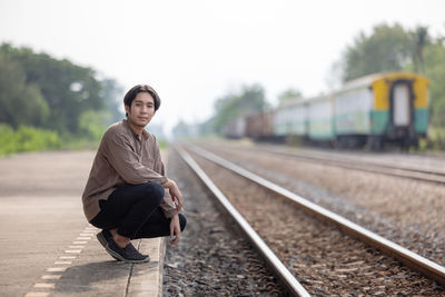 Depressed young man sitting on railway track person