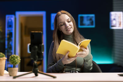 Portrait of young woman using mobile phone while sitting at home