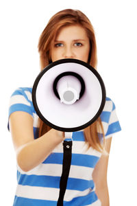 Portrait of young woman holding megaphone against white background