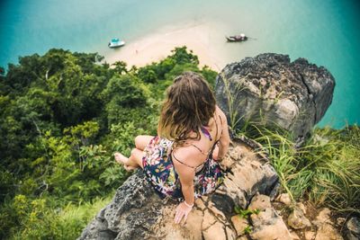 Rear view of young woman on rock at beach