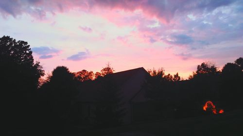 Silhouette houses and trees against sky at sunset