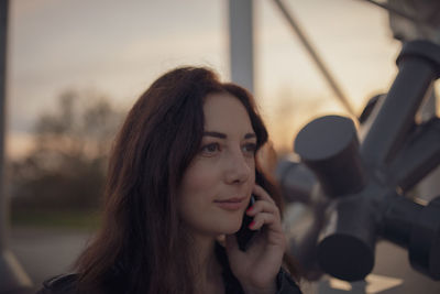 Close-up of thoughtful woman talking on phone during sunset