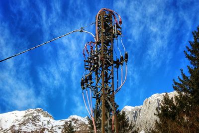 Low angle view of electric tower against blue sky