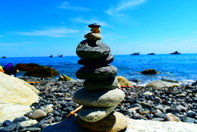 Stack of stones at beach against sky