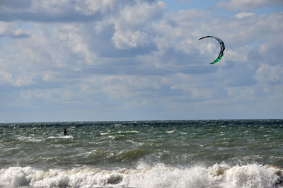 Person kiteboarding in sea against sky