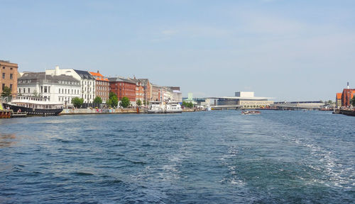 Sea by buildings against sky in city