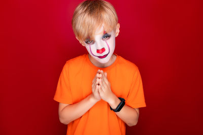 Portrait of boy holding red light against orange background