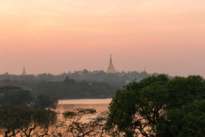 View of trees and building against sky during sunset