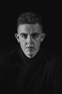 Close-up portrait of young man against black background