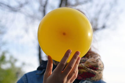 Close-up of hand holding yellow balloon