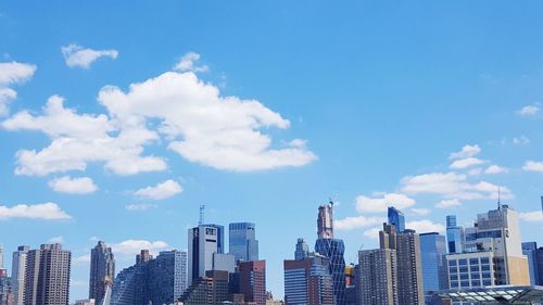 Low angle view of skyscrapers against cloudy sky