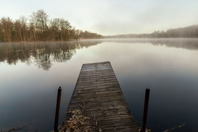 Pier on calm lake against sky