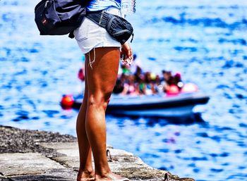 Low section of man standing on boat in sea