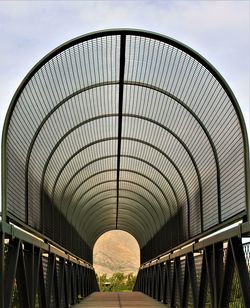 Looking into a metal bridge with a canopy, the mountains are in the distance. 