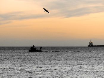 Silhouette boat sailing on sea against sky during sunset